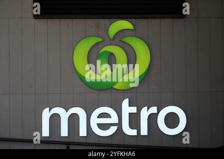 Logo della Woolworths Metro illuminato su un muro vicino all'ingresso di uno dei loro negozi di alimentari Foto Stock