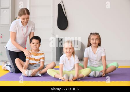 Bambini piccoli carini che si allungano con l'allenatore in palestra Foto Stock