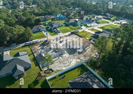 Veduta aerea dei costruttori che lavorano su una casa residenziale non finita con struttura di telaio del tetto in legno in costruzione nella zona suburbana della Florida. Foto Stock