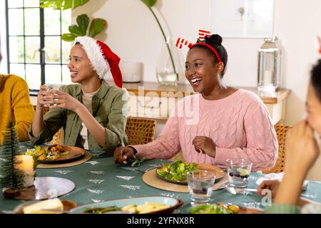 Natale, giovani amici multirazziali che si godono un pasto festivo insieme, a casa Foto Stock