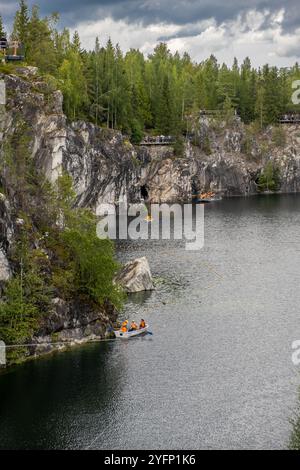 I visitatori pagaiano in kayak attraverso le calme acque del Marble Canyon, circondati da vegetazione lussureggiante e scogliere rocciose in Carelia Foto Stock