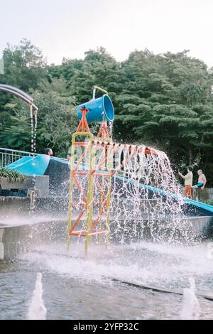 Bogor, 26 ottobre 2024. Cascata artificiale che fuoriesce da un secchio, ricicla l'acqua della piscina in una giocosa cascata, aggiungendo un tocco divertente e rinfrescante Foto Stock