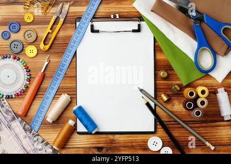 Colorate forniture di cucito disposte intorno a un portadocumenti vuoto su un tavolo di legno Foto Stock