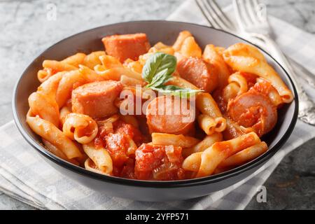 Treccione a spirale con salsicce affumicate in salsa piccante di pomodoro da vicino nel recipiente sul tavolo. Orizzontale Foto Stock