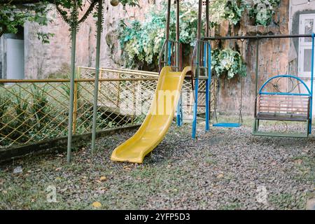 Parco giochi con scivolo e altalene in un lussuoso complesso residenziale, che offre un'area giochi sicura ed elegante per i bambini circondata dal verde Foto Stock