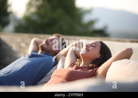 Coppia felice che si rilassa seduto su un divano terrazzo Foto Stock