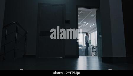 Un giovane uomo d'affari entra in una moderna e luminosa sala ufficio, parla con i partner commerciali telefonicamente. L'impiegato riceve notizie negative sul licenziamento o sul mancato successo di un accordo finanziario tramite telefonata. Colpo pieno. Foto Stock