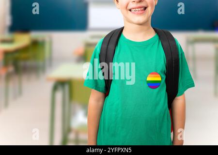 Il ragazzo in t-shirt verde con il simbolo dell'arcobaleno indossa lo zaino in classe al chiuso Foto Stock