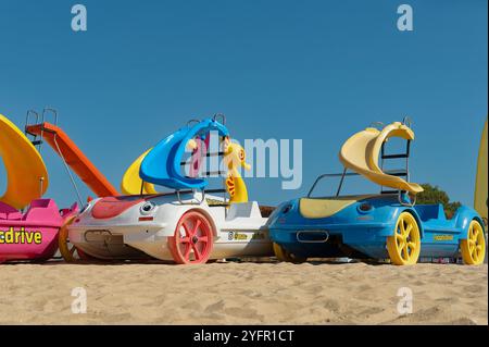 Barche a pedali colorate con scivoli si trovano su una spiaggia sabbiosa dell'Algarve Foto Stock