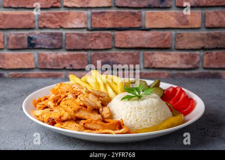 Donatore di pollo su pilaf con patatine fritte e sottaceti Foto Stock