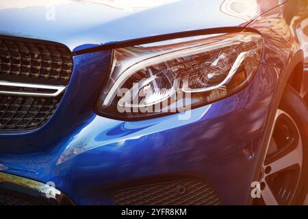 Bel faro di un'auto blu da vicino in una giornata di sole. Gentile con al lato Foto Stock