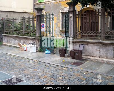 Cremona, Lombardia, Italia 27 ottobre 2024 traboccanti di rifiuti e scatole di cartone si trovano su un marciapiede di fronte ad un vecchio edificio, evidenziando la spreco Foto Stock