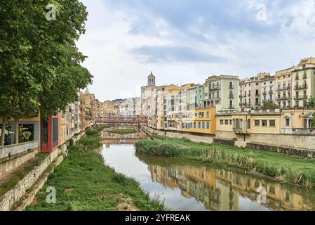 Vista della città vecchia di Girona, Catalogna, Spagna, Europa. Viaggi estivi. Case colorate gialle e arancioni e ponte Pont de Sant Agusti riflessi nell'acqua Foto Stock