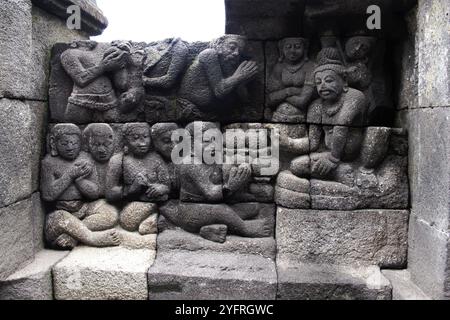 Sculture a bassorilievo sulla parete incassate a piedi di Borobudur, Indonesia Foto Stock