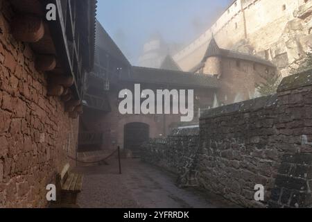 Castello fortificato di Haut Koenigsbourg nella nebbia mattutina. Ponti levatoi, stanza delle armi, fortezza di montagna e cannoni. Alsazia, Francia, Europa Foto Stock