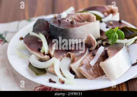 sgombro leggermente salato con cipolle e spezie, in un piatto su un tavolo di legno. Foto Stock