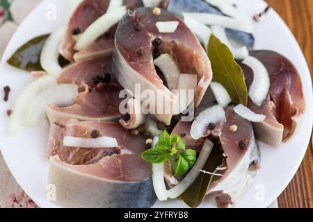sgombro leggermente salato con cipolle e spezie, in un piatto su un tavolo di legno. Foto Stock