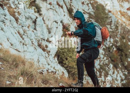 Un escursionista maschile che guarda il monitor guarda controllare la frequenza cardiaca durante le escursioni in montagna avventura viaggiare sport estremi vita attiva all'aperto. Alto Foto Stock