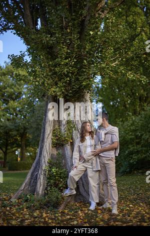 Giovane ragazza carina fidanzata degli abbracci. In autunno, Outdoor. Lovers Walking in Park. Bella coppia divertente. Lovestory in Forest. Uomo e donna. Carini amanti Foto Stock