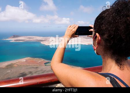 Vista posteriore di una turista che scatta foto dell'isola Foto Stock