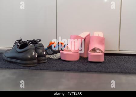 Scarpe da famiglia davanti a un armadio, sneakers da uomo, scarpe da bambino e tacchi alti con pinkte. Foto di alta qualità Foto Stock