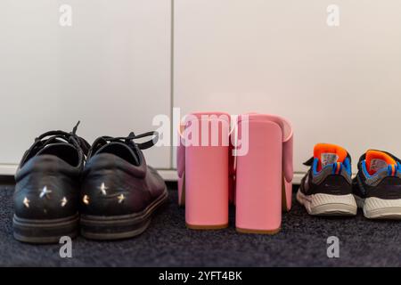 Scarpe da famiglia davanti a un armadio, sneakers da uomo, scarpe da bambino e tacchi alti con pinkte. Foto di alta qualità Foto Stock