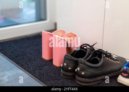 Scarpe da famiglia davanti a un armadio, sneakers da uomo, scarpe da bambino e tacchi alti con pinkte. Foto di alta qualità Foto Stock