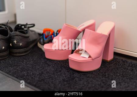 Scarpe da famiglia davanti a un armadio, sneakers da uomo, scarpe da bambino e tacchi alti con pinkte. Foto di alta qualità Foto Stock