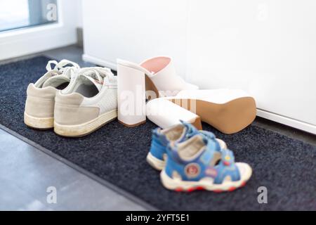 Scarpe da famiglia davanti a un armadio, sneakers da uomo, scarpe da bambino e tacchi alti bianchi. Foto di alta qualità Foto Stock