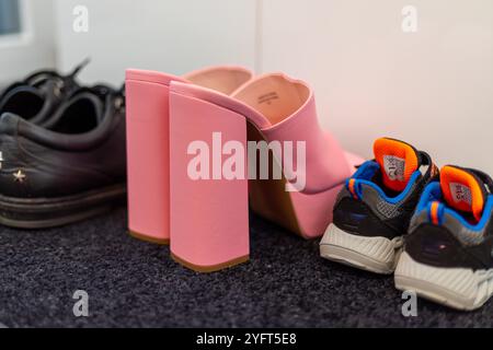 Scarpe da famiglia davanti a un armadio, sneakers da uomo, scarpe da bambino e tacchi alti con pinkte. Foto di alta qualità Foto Stock