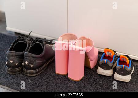 Scarpe da famiglia davanti a un armadio, sneakers da uomo, scarpe da bambino e tacchi alti con pinkte. Foto di alta qualità Foto Stock