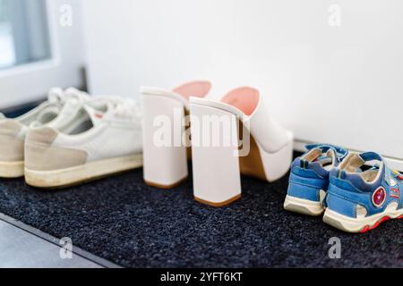 Scarpe da famiglia davanti a un armadio, sneakers da uomo, scarpe da bambino e tacchi alti bianchi. Foto di alta qualità Foto Stock