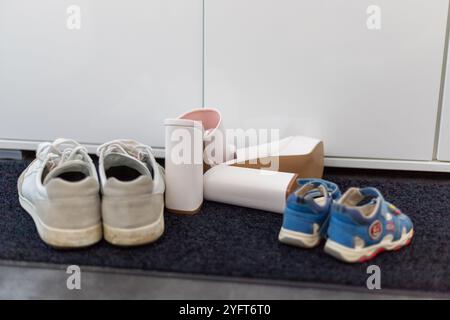 Scarpe da famiglia davanti a un armadio, sneakers da uomo, scarpe da bambino e tacchi alti bianchi. Foto di alta qualità Foto Stock