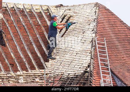 Un conciatetto che lavora su una casa per sostituire un tetto che era stato spruzzato con schiuma a Gloucester, Inghilterra, Regno Unito Foto Stock