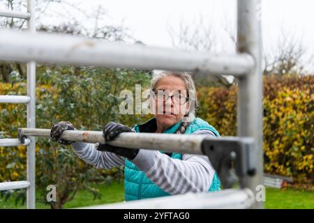 Gerüstbauerin, Malerin baut ein mobiles Gerüst am Einfamilienhaus auf, modello rilasciato für redaktionelle Nutzung, Gerüstbauer *** Scaffolder, pittore erige ponteggi mobili su una casa indipendente, modello rilasciato per uso editoriale, ponteggio 20241105-DSC 8671 Foto Stock