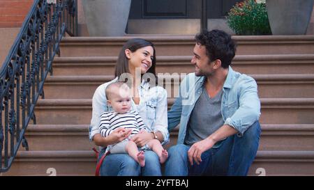 La famiglia con la bambina seduto a pochi passi dall'esterno di casa in Urban Street a New York City USA Foto Stock