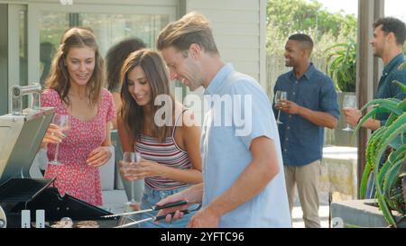Gruppo di giovani amici che amano il barbecue all'aperto a casa insieme Foto Stock