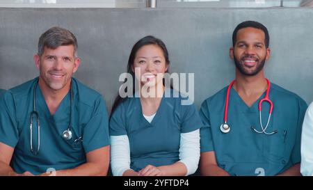 Ritratto della squadra medica o chirurgica multiculturale che indossa scrub seduti all'interno dell'ospedale insieme Foto Stock