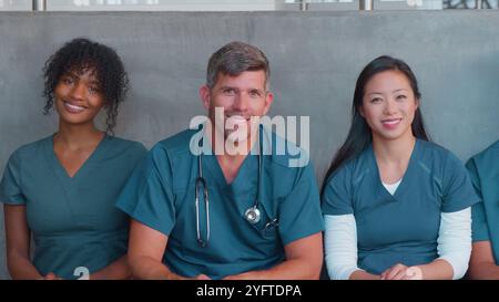 Ritratto della squadra medica o chirurgica multiculturale che indossa scrub seduti all'interno dell'ospedale insieme Foto Stock