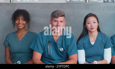 Ritratto della squadra medica o chirurgica multiculturale che indossa scrub seduti all'interno dell'ospedale insieme Foto Stock