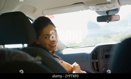 La madre parla con i bambini sul sedile posteriore dell'auto durante la vacanza in famiglia Foto Stock