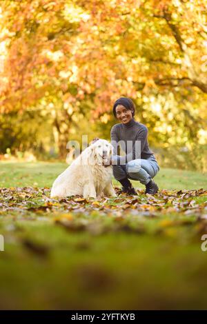 Ritratto della giovane donna che cammina PET Golden Retriever Dog al guinzaglio nella campagna autunnale Foto Stock