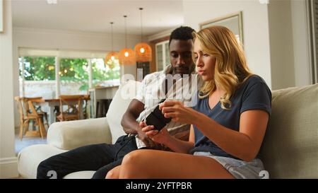 Due amici giocano eccitatamente ai videogiochi su un divano. Foto Stock