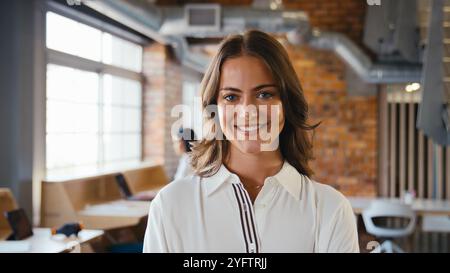 Ritratto di una giovane donna d'affari sorridente che lavora in un moderno ufficio open space Foto Stock