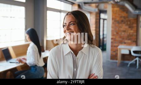 Ritratto di una giovane donna d'affari sorridente che lavora in un moderno ufficio open space Foto Stock