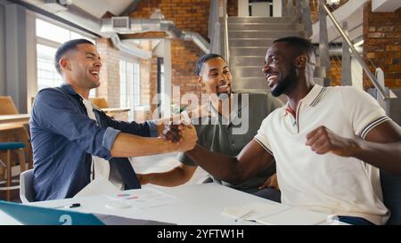 Gli uomini d'affari si riuniscono in un ufficio moderno seduto intorno al tavolo per celebrare il lancio di documenti nell'aria Foto Stock