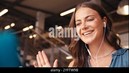 Primo piano di una donna d'affari in ufficio moderno che effettua videochiamate indossando auricolari o auricolari Foto Stock