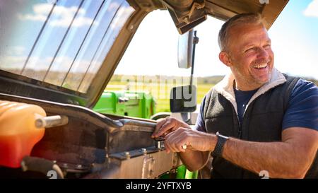 Primo piano dei macchinari per la riparazione dei lavoratori agricoli maschi maturi Foto Stock
