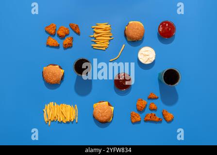 Vista panoramica con cheeseburger, pepite di pollo, patatine fritte, salse e bevande isolate su sfondo blu Foto Stock