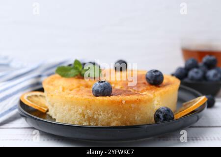 Deliziosa torta di semola con mirtilli e fette d'arancia su un tavolo di legno bianco, primo piano Foto Stock